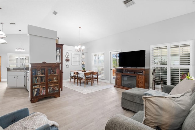 7923 Woburn St, New Port Richey, FL 34653 - living area featuring a chandelier, light wood-style flooring, baseboards, and high vaulted ceiling