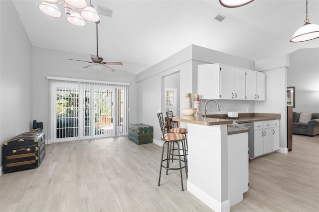 7923 Woburn St, New Port Richey, FL 34653 - kitchen featuring open floor plan, vaulted ceiling, light wood-style floors, dark countertops, and white cabinets