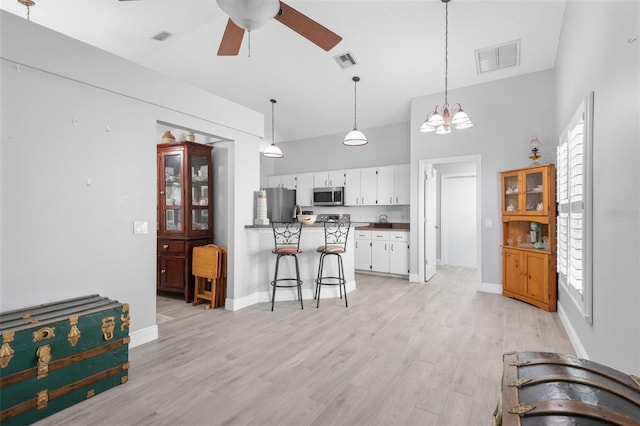 7923 Woburn St, New Port Richey, FL 34653 - kitchen featuring stainless steel appliances, a ceiling fan, white cabinets, dark countertops, and a breakfast bar area