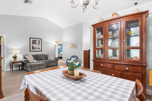7923 Woburn St, New Port Richey, FL 34653 - dining area featuring a chandelier, vaulted ceiling, light wood-style floors, and baseboards
