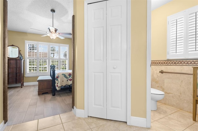 7923 Woburn St, New Port Richey, FL 34653 - bathroom featuring a closet, a ceiling fan, toilet, a wainscoted wall, and tile patterned floors