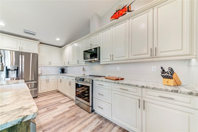 4469 Bahama Dr, Hernando Beach, FL 34607 - kitchen with stainless steel appliances, recessed lighting, light wood-type flooring, white cabinets, and light stone countertops