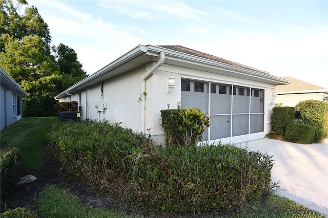 14112 Whitecap Ave, Hudson, FL 34667 - view of side of home featuring concrete driveway, a garage, stucco siding, and central air condition unit