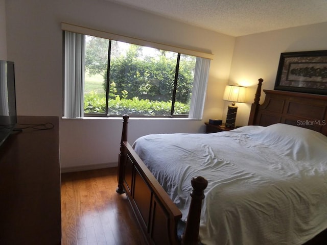 13010 Wedgewood Way Unit A, Hudson, FL 34667 - bedroom featuring multiple windows, wood finished floors, a textured ceiling, and baseboards