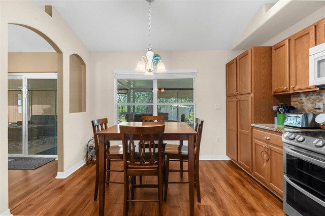 13444 English Parrot Rd, Brooksville, FL 34614 - dining area featuring a chandelier, dark wood-type flooring, baseboards, arched walkways, and lofted ceiling