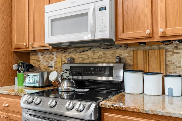 13444 English Parrot Rd, Brooksville, FL 34614 - kitchen featuring white microwave, stainless steel range with electric stovetop, backsplash, brown cabinetry, and light stone countertops