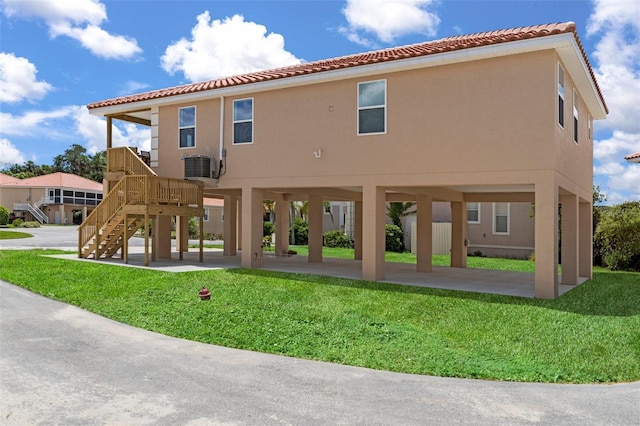 10234 W Middlburg Loop Unit 152, Homosassa, FL 34448 - rear view of house featuring a tiled roof, a lawn, a carport, stucco siding, and stairway