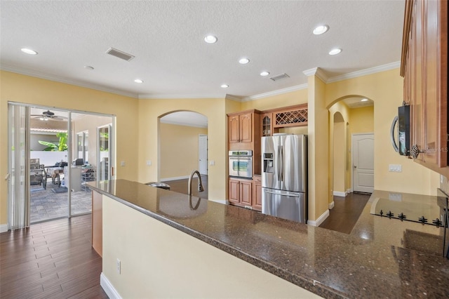 11726 Belle Haven Dr, New Port Richey, FL 34654 - kitchen with stainless steel appliances, arched walkways, dark stone counters, dark wood-style flooring, and ceiling fan