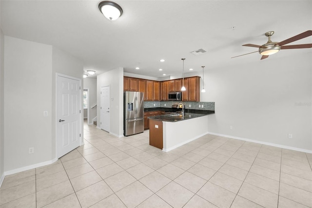 5032 Sand Castle Dr, New Port Richey, FL 34652 - kitchen with appliances with stainless steel finishes, a peninsula, dark countertops, backsplash, and light tile patterned flooring