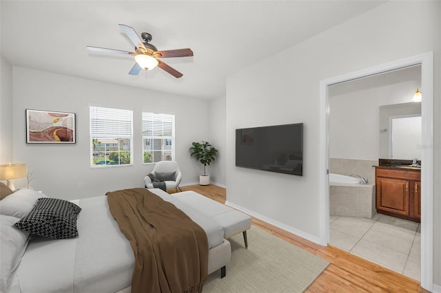 5032 Sand Castle Dr, New Port Richey, FL 34652 - bedroom with light wood-style flooring, connected bathroom, and ceiling fan