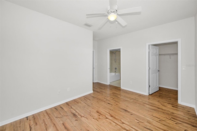 5032 Sand Castle Dr, New Port Richey, FL 34652 - unfurnished bedroom with light wood-style floors, a walk in closet, a closet, ensuite bath, and a ceiling fan