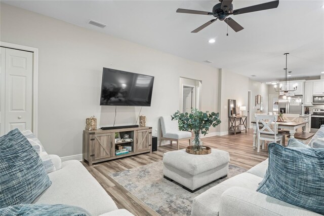 1601 E 98th Ave, Tampa, FL 33612 - living room with baseboards, ceiling fan, light wood finished floors, a chandelier, and recessed lighting
