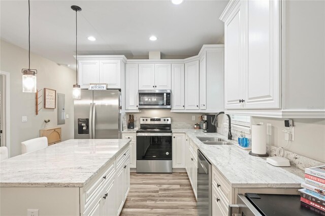 1601 E 98th Ave, Tampa, FL 33612 - kitchen featuring appliances with stainless steel finishes, a sink, light wood-style floors, white cabinetry, and a center island