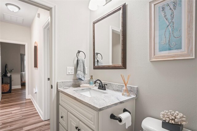 1601 E 98th Ave, Tampa, FL 33612 - half bath featuring vanity, toilet, wood finished floors, and baseboards