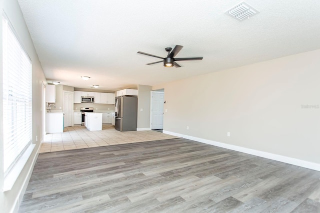 10386 Norvell Rd, Spring Hill, FL 34608 - unfurnished living room with light wood-type flooring, ceiling fan, and a textured ceiling