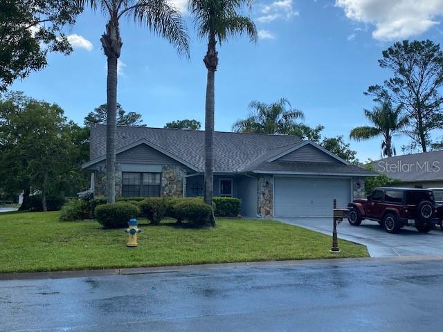 10301 Ravines Dr, New Port Richey, FL 34654 - single story home with an attached garage, concrete driveway, a front lawn, and stone siding