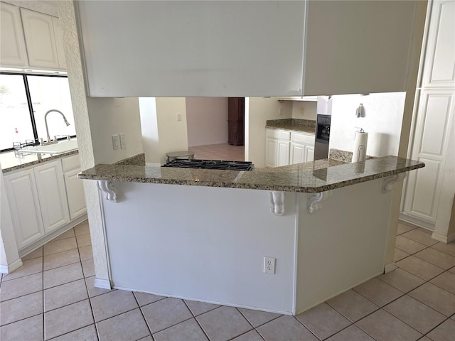 10244 Hoover St, Spring Hill, FL 34608 - kitchen with light tile patterned floors, a breakfast bar, white refrigerator with ice dispenser, white cabinetry, and stovetop