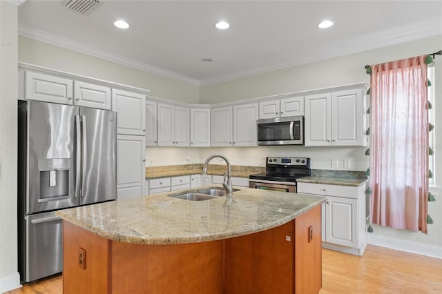 1010 Teal Pointe, Tarpon Springs, FL 34689 - kitchen with stainless steel appliances, ornamental molding, light wood-style floors, a center island with sink, and light stone countertops