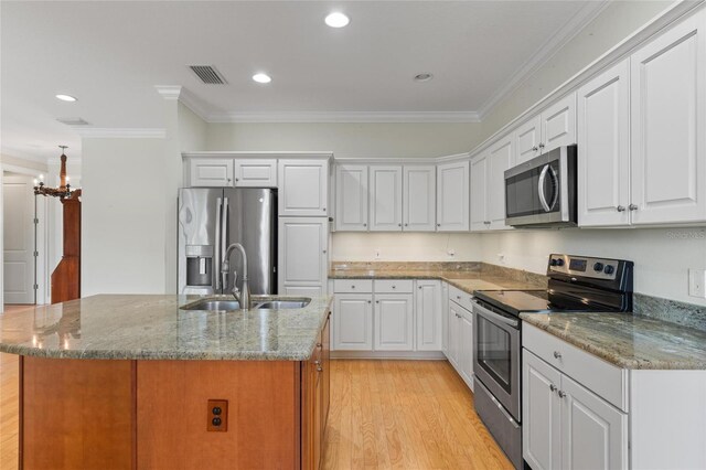 1010 Teal Pointe, Tarpon Springs, FL 34689 - kitchen with appliances with stainless steel finishes, ornamental molding, light wood-type flooring, a center island with sink, and white cabinets