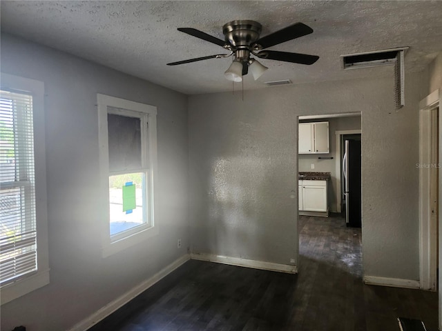 3415 N 51st St, Tampa, FL 33619 - empty room with dark wood finished floors, healthy amount of natural light, a textured ceiling, and baseboards