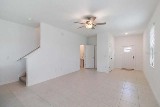 8305 Crescent Oaks Dr, New Port Richey, FL 34655 - unfurnished living room featuring a ceiling fan, stairway, and light tile patterned floors