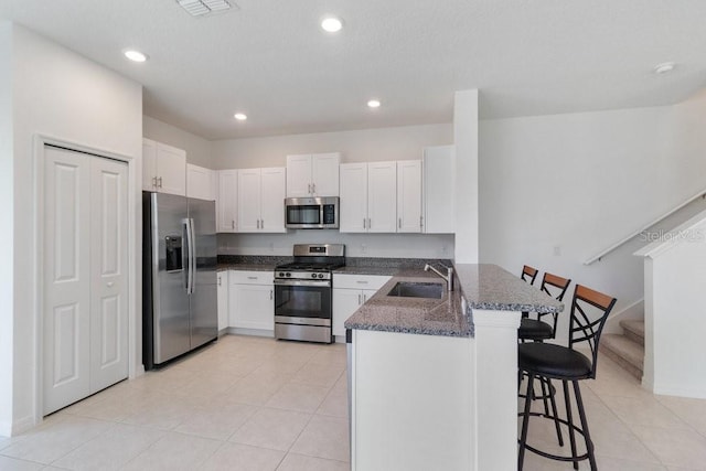 8305 Crescent Oaks Dr, New Port Richey, FL 34655 - kitchen with appliances with stainless steel finishes, a peninsula, a breakfast bar, dark stone counters, and white cabinets