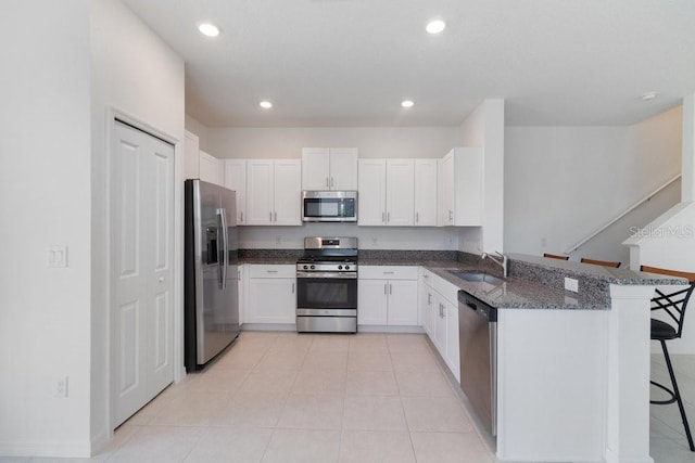 8305 Crescent Oaks Dr, New Port Richey, FL 34655 - kitchen with appliances with stainless steel finishes, a kitchen breakfast bar, dark stone counters, a peninsula, and white cabinetry
