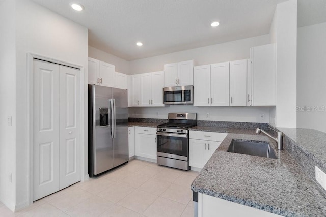 8305 Crescent Oaks Dr, New Port Richey, FL 34655 - kitchen featuring appliances with stainless steel finishes, dark stone counters, white cabinets, recessed lighting, and light tile patterned floors