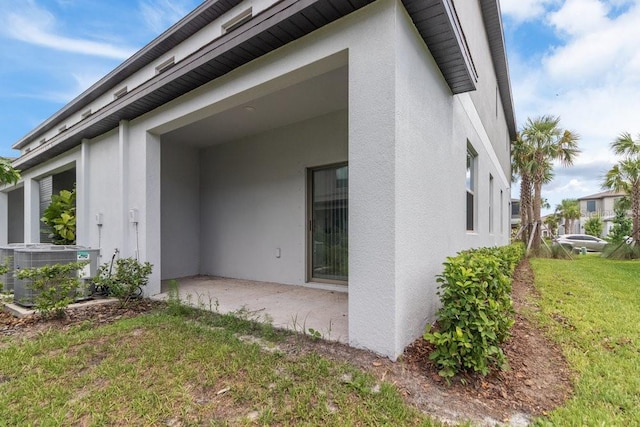 8305 Crescent Oaks Dr, New Port Richey, FL 34655 - view of home's exterior featuring stucco siding, a patio area, and a lawn