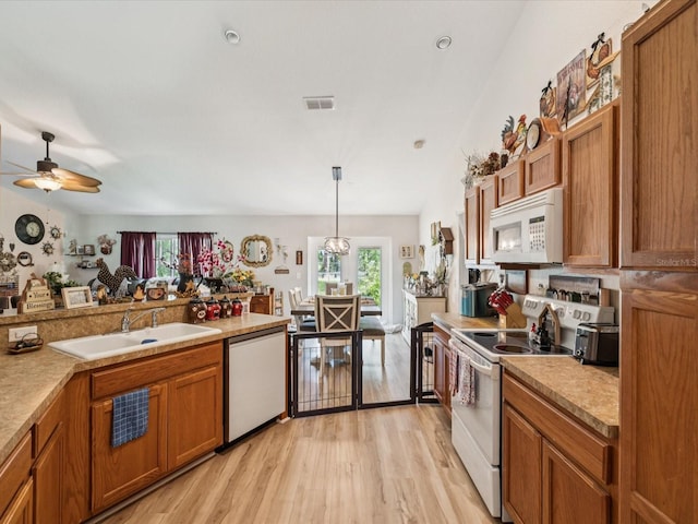 12229 Barnevelde Rd, Weeki Wachee, FL 34614 - kitchen with white appliances, a sink, light wood-style floors, brown cabinetry, and a ceiling fan