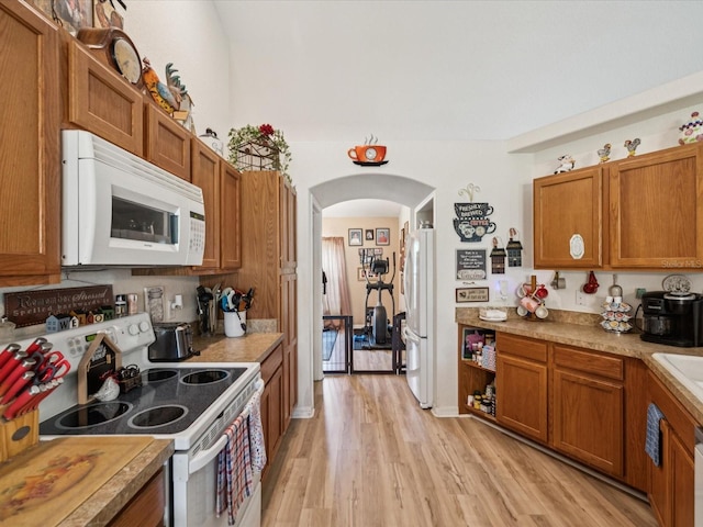 12229 Barnevelde Rd, Weeki Wachee, FL 34614 - kitchen featuring white appliances, brown cabinetry, and light wood-style flooring
