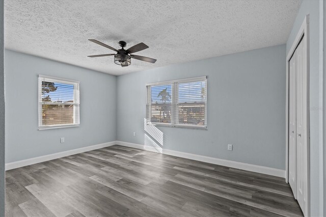 13821 Judy Ave, Hudson, FL 34667 - unfurnished bedroom with multiple windows, dark wood-style floors, a textured ceiling, and a closet