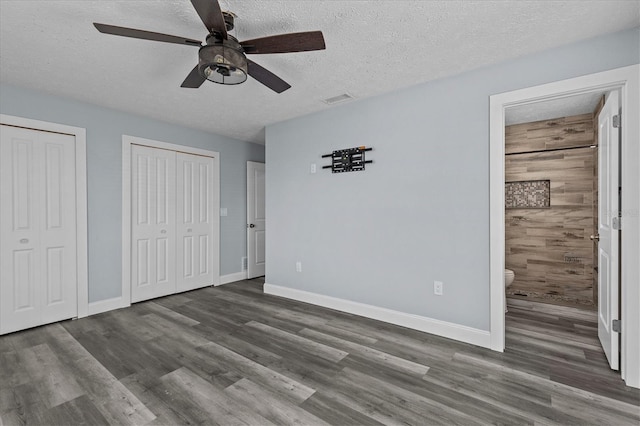 13821 Judy Ave, Hudson, FL 34667 - unfurnished bedroom featuring two closets, wood finished floors, a textured ceiling, and baseboards