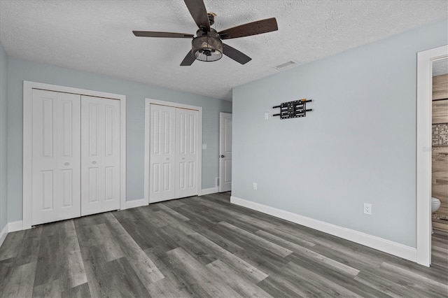 13821 Judy Ave, Hudson, FL 34667 - unfurnished bedroom featuring two closets, wood finished floors, baseboards, a textured ceiling, and connected bathroom
