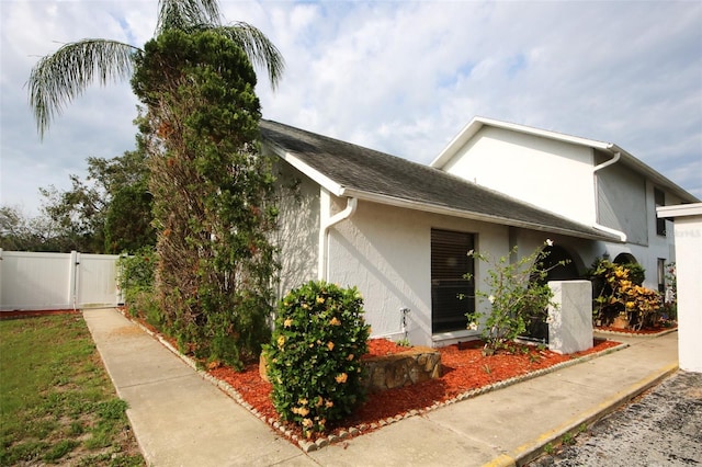 6806 Beach Blvd, Hudson, FL 34667 - view of side of home featuring stucco siding and a gate