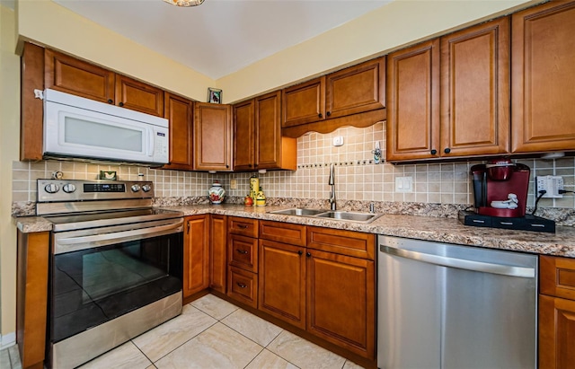 3841 Lanyard Ct Unit B, New Port Richey, FL 34652 - kitchen featuring appliances with stainless steel finishes, brown cabinetry, tasteful backsplash, and light tile patterned flooring