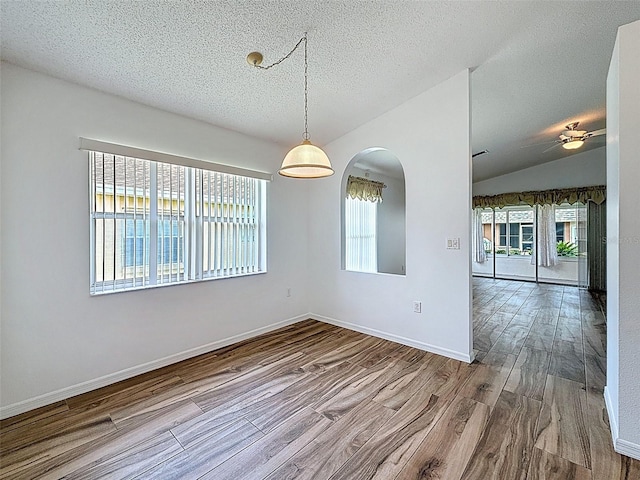 3317 Abigail Ct, New Port Richey, FL 34655 - unfurnished room with healthy amount of natural light, wood finished floors, arched walkways, a textured ceiling, and lofted ceiling
