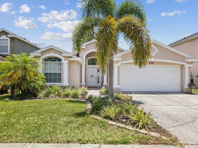 4716 Wolfram Ln, New Port Richey, FL 34653 - view of front of house featuring a garage, a front yard, stucco siding, and concrete driveway