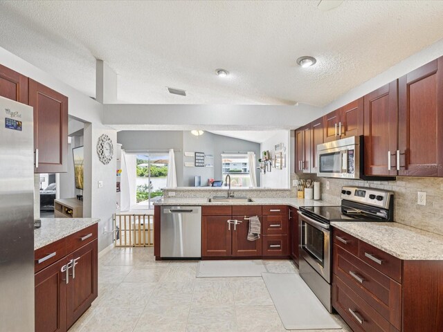 4716 Wolfram Ln, New Port Richey, FL 34653 - kitchen with stainless steel appliances, a peninsula, a textured ceiling, dark brown cabinets, and decorative backsplash
