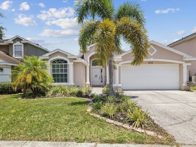 4716 Wolfram Ln, New Port Richey, FL 34653 - view of front of house with an attached garage, a front yard, stucco siding, and driveway