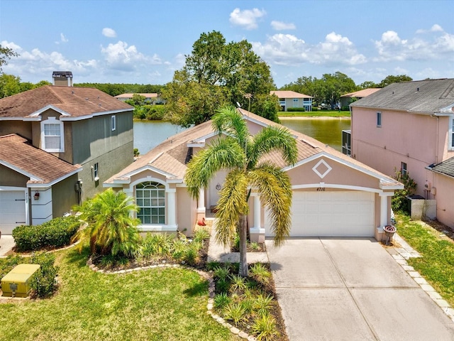 4716 Wolfram Ln, New Port Richey, FL 34653 - view of front facade with a water view, an attached garage, driveway, a residential view, and stucco siding