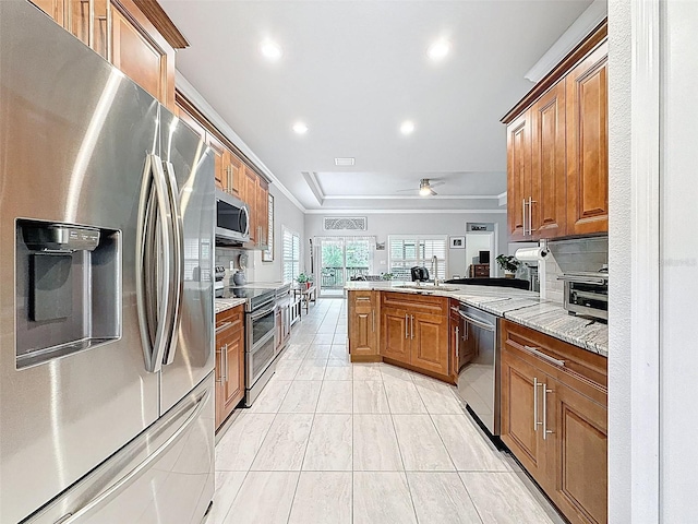 4082 Watson Dr, New Port Richey, FL 34655 - kitchen with appliances with stainless steel finishes, crown molding, a peninsula, brown cabinetry, and backsplash
