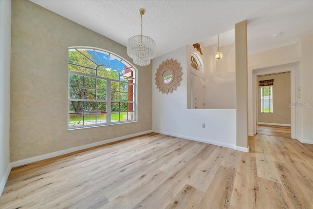 9130 Madrid Rd, Weeki Wachee, FL 34613 - spare room with wood finished floors, healthy amount of natural light, a chandelier, a textured ceiling, and a smoke detector