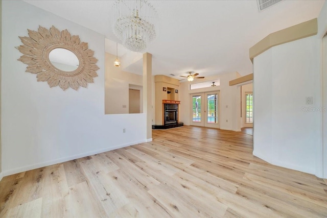 9130 Madrid Rd, Weeki Wachee, FL 34613 - unfurnished living room featuring wood finished floors, a chandelier, a glass covered fireplace, and ceiling fan