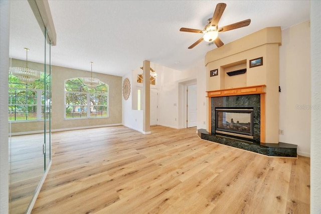 9130 Madrid Rd, Weeki Wachee, FL 34613 - unfurnished living room with wood finished floors, a fireplace, a chandelier, and a ceiling fan