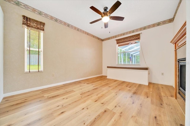 9130 Madrid Rd, Weeki Wachee, FL 34613 - unfurnished living room featuring light wood-type flooring, crown molding, a ceiling fan, and a glass covered fireplace