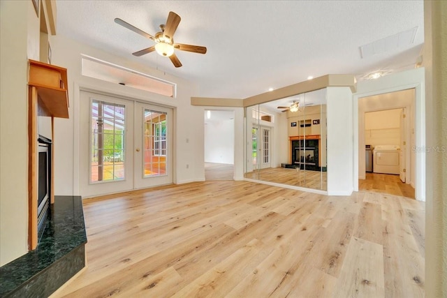 9130 Madrid Rd, Weeki Wachee, FL 34613 - unfurnished living room featuring a tiled fireplace, french doors, washing machine and clothes dryer, a ceiling fan, and wood finished floors