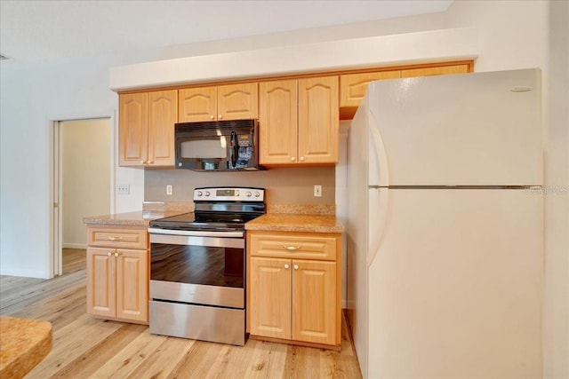 9130 Madrid Rd, Weeki Wachee, FL 34613 - kitchen with black microwave, freestanding refrigerator, electric stove, light brown cabinets, and light wood finished floors