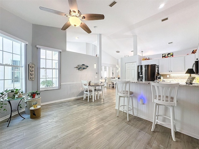 7518 Mediterranean Ct, Hudson, FL 34667 - kitchen featuring stainless steel fridge with ice dispenser, light wood-type flooring, white cabinetry, a peninsula, and lofted ceiling