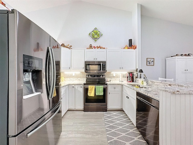 7518 Mediterranean Ct, Hudson, FL 34667 - kitchen featuring appliances with stainless steel finishes, a peninsula, light stone counters, light wood-type flooring, and decorative backsplash